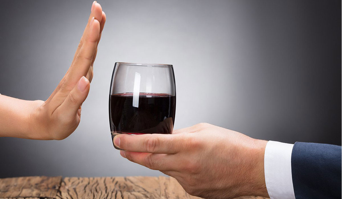Одна рука дает бокал вина, другая рука отказывается.